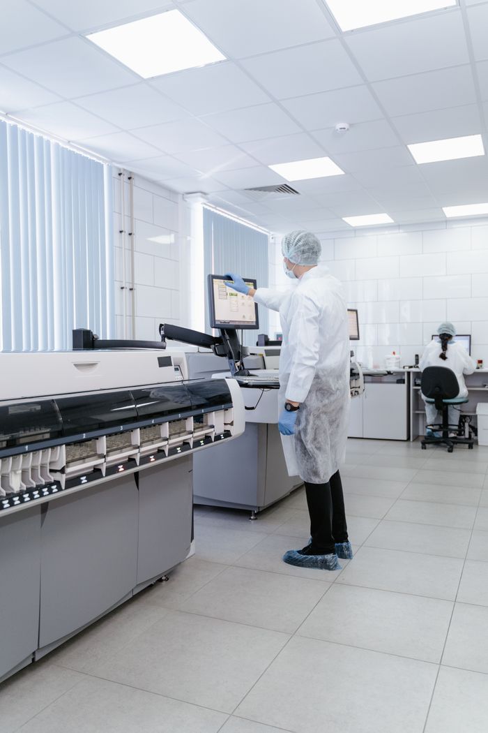 Crafting Captivating Headlines: Your awesome post title goes here Technician in PPE working with advanced lab equipment in a modern medical laboratory.